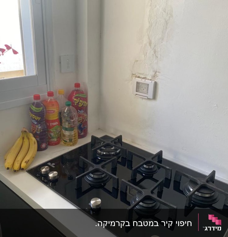 קיר עם סימני תיקון ליד כיריים במטבח